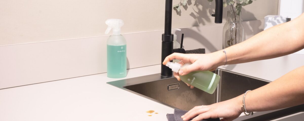 a woman is cleaning a kitchen sink with a rag