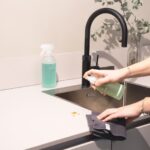 a woman is cleaning a kitchen sink with a rag