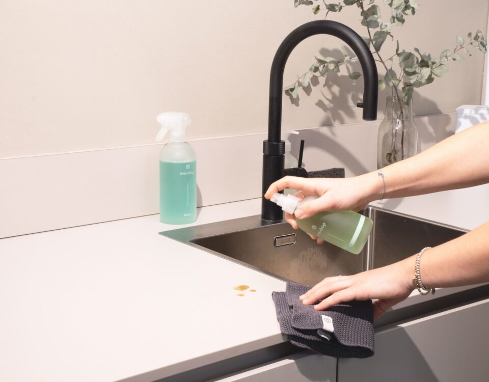 a woman is cleaning a kitchen sink with a rag